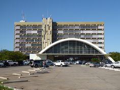 cars parked in front of a large building on a parking lot with stairs leading up to it