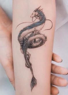 a woman's arm with a dragon tattoo on it and a snake wrapped around the arm