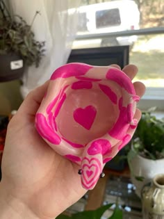 a hand holding a pink heart shaped bowl