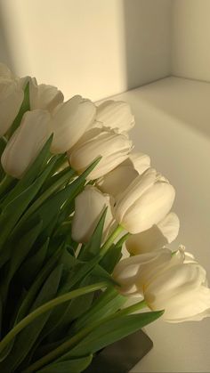 a bouquet of white tulips sitting on top of a table