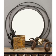 a clock sitting on top of a wooden table next to two horns and a cow skull