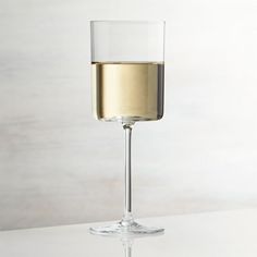 a glass filled with white wine sitting on top of a table