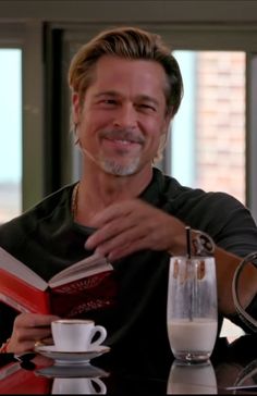 a man sitting at a table with a book and coffee mug in front of him