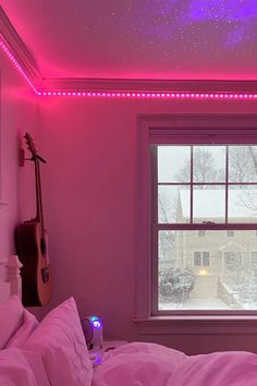 a bedroom with pink walls and purple lights on the ceiling is lit up by an electric guitar