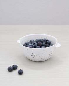 a white bowl filled with blueberries on top of a table