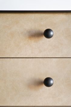 two black knobs on a tan dresser drawer