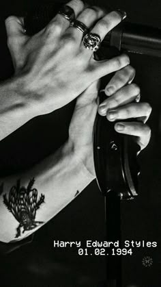 two hands holding onto each other with tattoos on their arms and wrist, in black and white