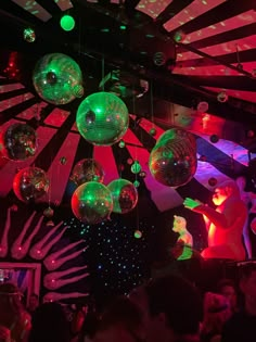 many disco balls hanging from the ceiling in a room with people dancing and lights on