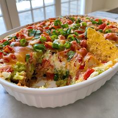 a white dish filled with mexican food and tortilla chips on top of it