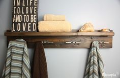 towels are hanging on a shelf in a bathroom with towel rack and wooden sign above it