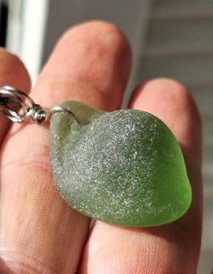 a person holding a green piece of food in their hand with a chain attached to it