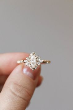 a woman's hand holding an engagement ring with a diamond center and side stones