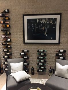 two gray chairs sitting in front of a wine rack filled with bottles and glasses on top of a table