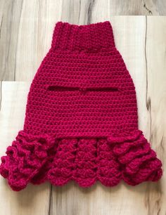 a pink crocheted skirt with ruffles on the bottom, sitting on a wooden floor