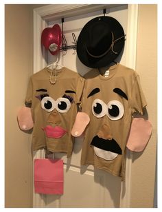 two t - shirts that have faces on them hanging from a door with a hat