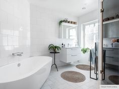 a bath room with a tub a sink and some rugs on the floor in front of a window