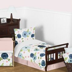 a child's bed with pink and blue flowers on the comforter, crib