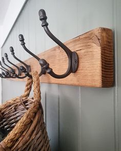 a wooden coat rack with hooks and rope hanging from it's sides next to a basket