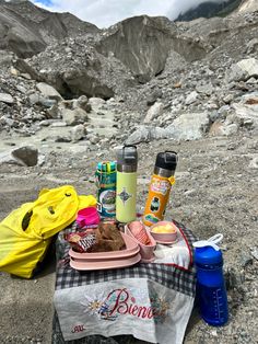 a picnic table with food and drinks on it in the middle of a rocky area