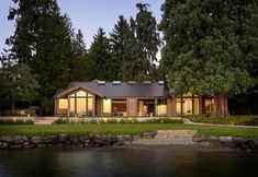 a house sitting on top of a lush green field next to a lake at night