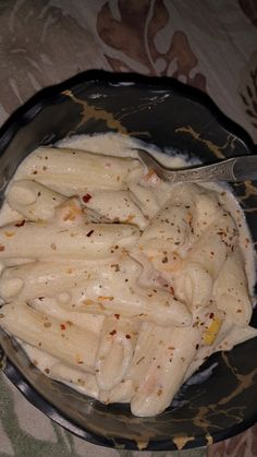 a bowl filled with pasta and sauce on top of a floral tablecloth covered table