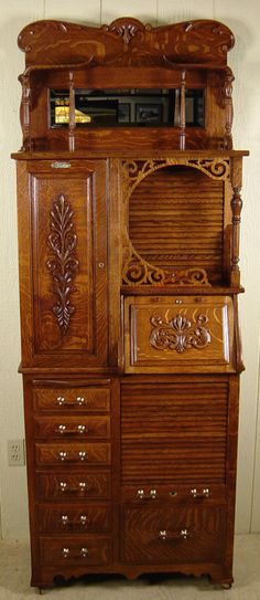 an old wooden dresser with carved carvings on the top and bottom drawers, sitting against a white wall