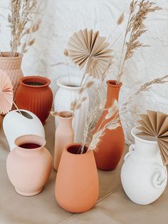 various vases with paper fans in them on a table