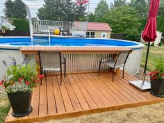 an above ground swimming pool with decking and patio furniture in the middle of it