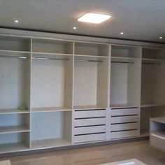 an empty room with white shelving and lights on the ceiling, in front of a window