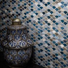 a vase sitting on top of a table next to a blue and white tiled wall