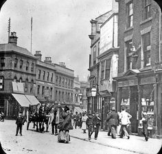 an old black and white photo of people walking down the street