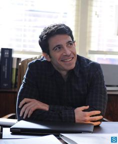 a man sitting at a table with a plate of food in front of him and smiling