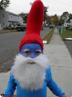 a man with blue paint on his face and white beard is standing in the street