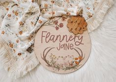 a wooden sign that says fancy jane with flowers and leaves around it on a white furnishing