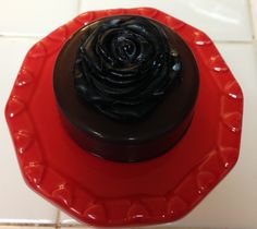 a chocolate cupcake sitting on top of a red plate next to a white tile floor