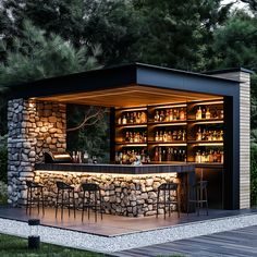 an outdoor bar with stone walls and barstools is lit up at night time