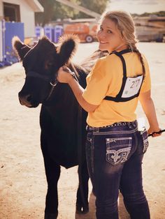 a woman is petting a small black cow