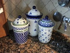 three blue and white canisters sitting on top of a counter next to a sink