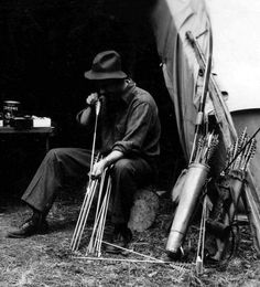 a man sitting in front of a tent with skis and poles