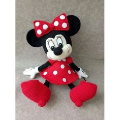 a red and white minnie mouse stuffed animal sitting on top of a floor next to a wall