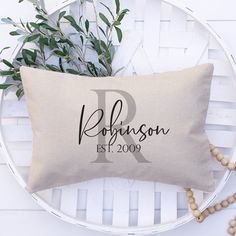 a personalized pillow sitting on top of a white chair next to a potted plant