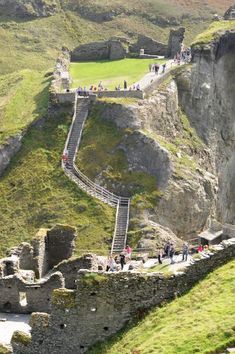 people are walking up and down the stairs to an old castle like structure on top of a hill