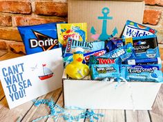 a box filled with candy and snacks on top of a wooden table next to a brick wall