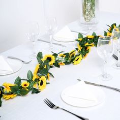 the table is set with sunflowers and silverware