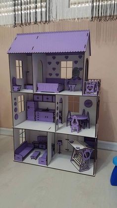 a doll house made out of cardboard with purple furniture and accessories on the top floor