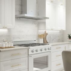 a kitchen with white cabinets and marble counter tops is pictured in this image, there are two chairs at the stove