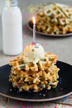 a stack of waffles topped with ice cream and sprinkles next to a bottle of milk