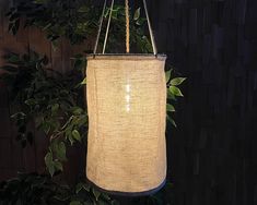 a lamp hanging from the ceiling in front of a wall with plants and leaves on it