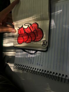 a notepad with graffiti on it is held up by someone's hand