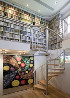 a spiral staircase in front of a book shelf filled with books